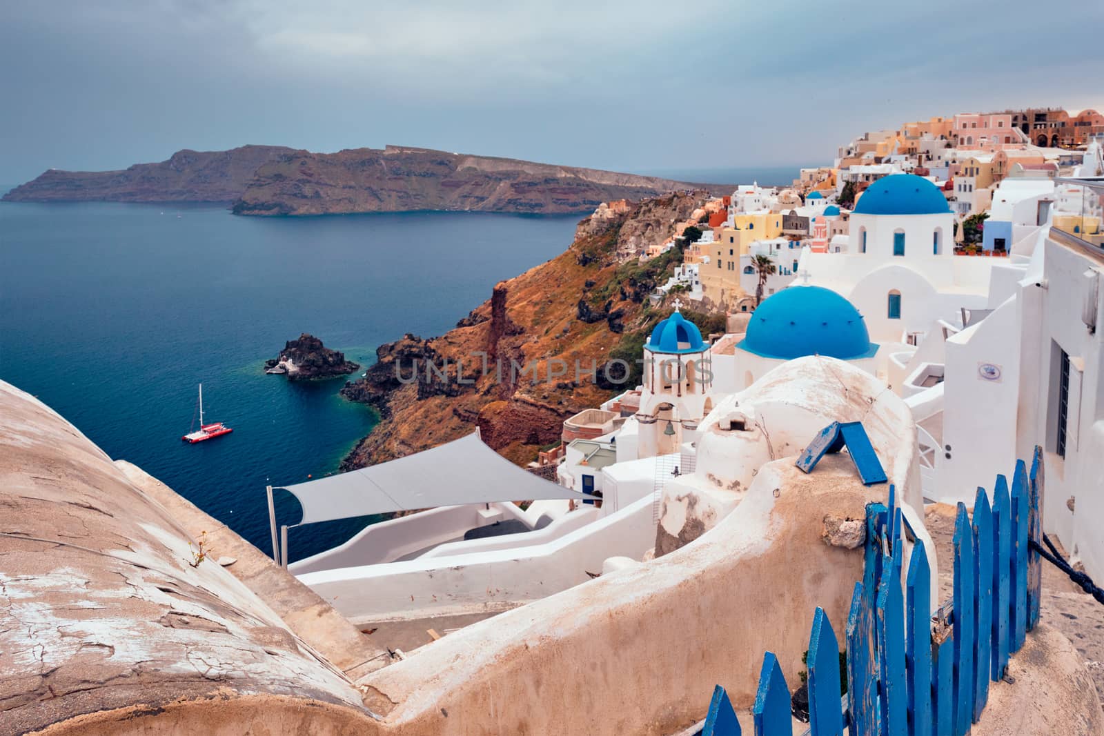Famous greek iconic selfie spot tourist destination Oia village with traditional white houses and church in Santorini island on sunset in twilight, Greece