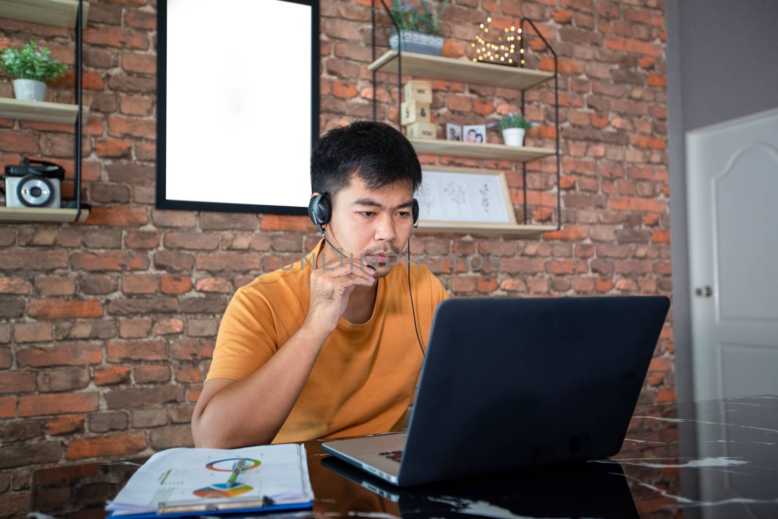 Asian businessmen is using notebook computers and wear headphones for online meetings and working from home.