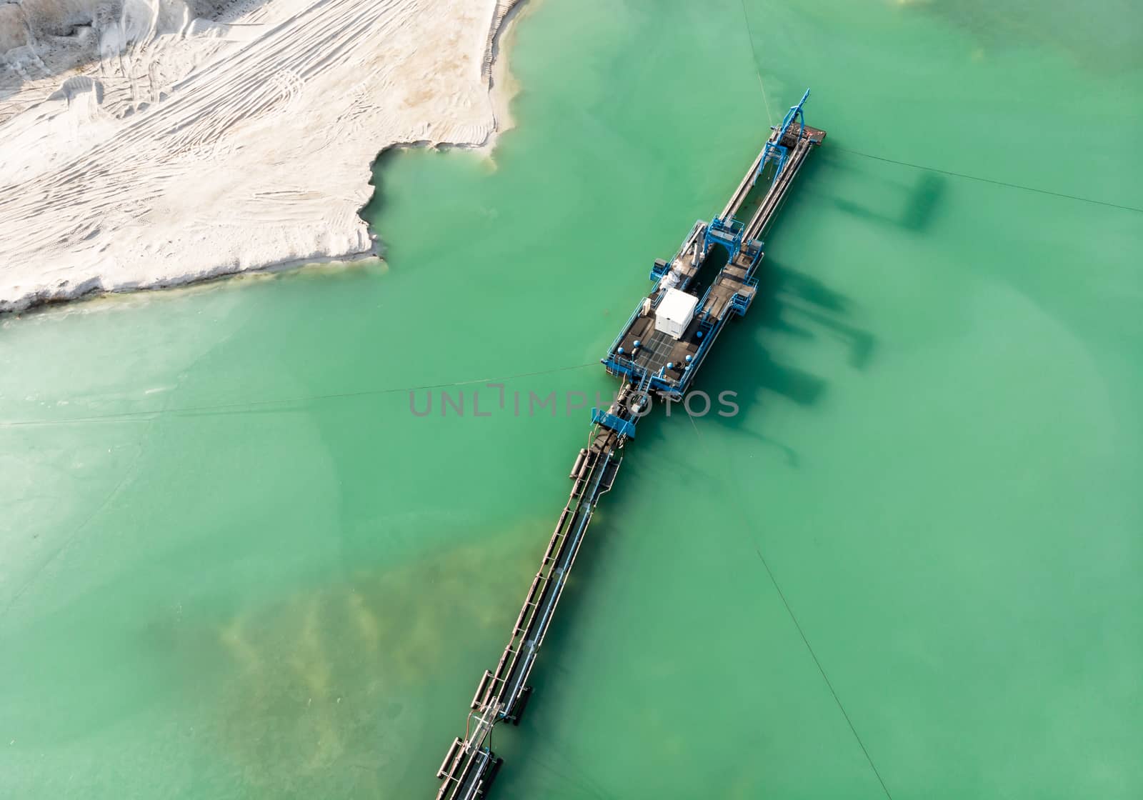 Aerial view of the long boom of a suction excavator in a quartz quarry for the excavation of white sand, made with drone