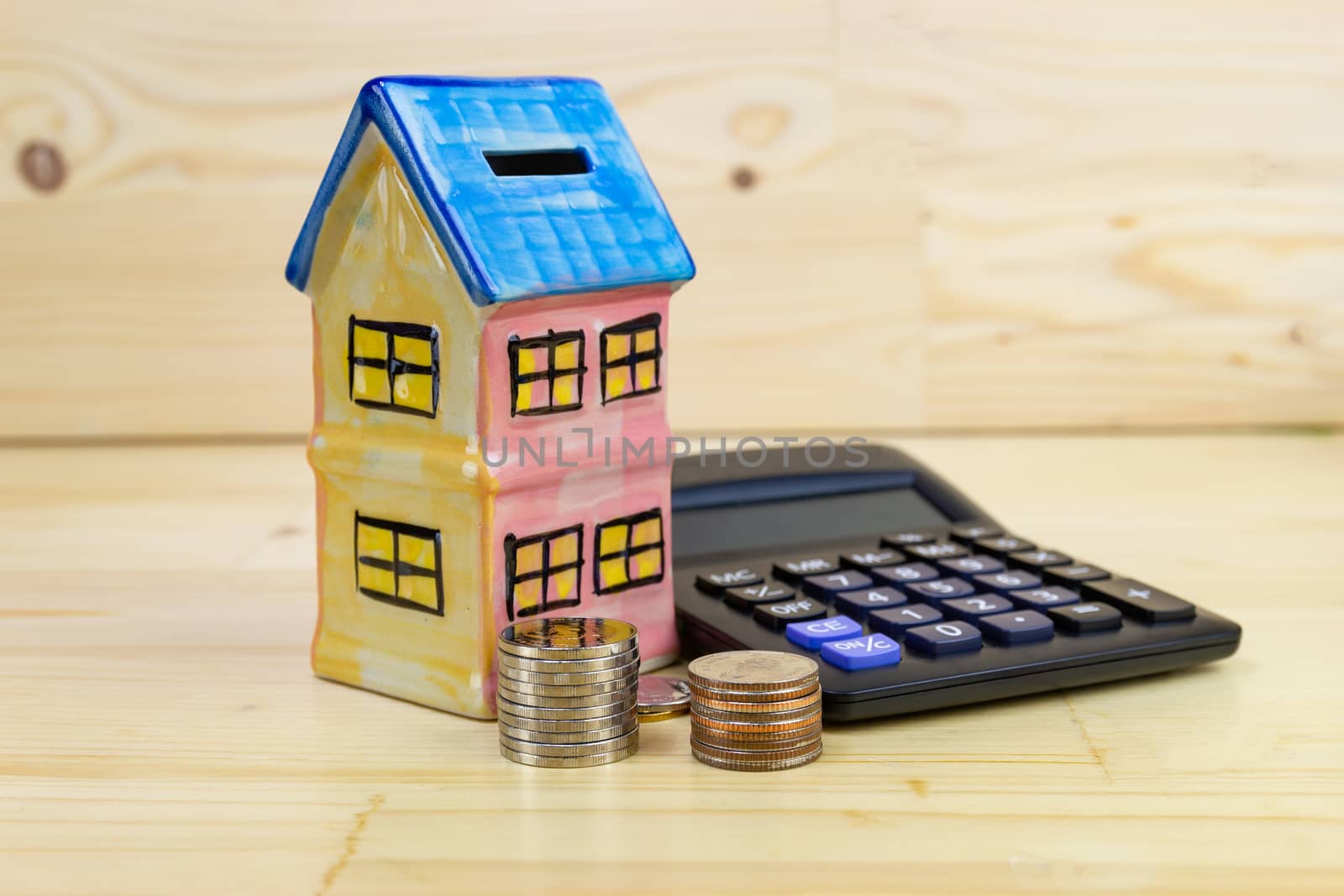 Model house with coin, calculator on wood table concept Collecting money Buying a house
