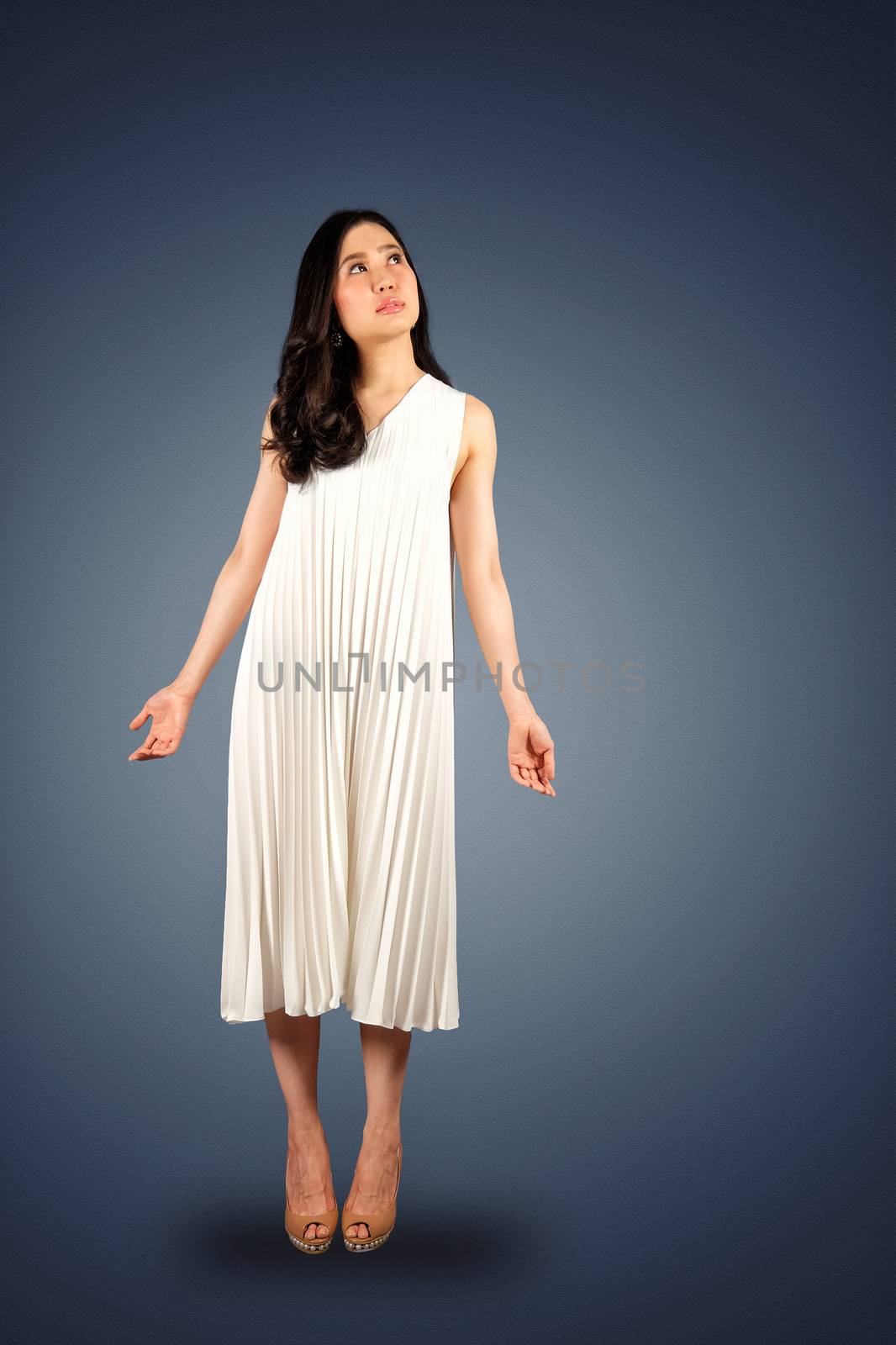 Young asian woman in white dress looking at the space for text on dark blue background with clipping path