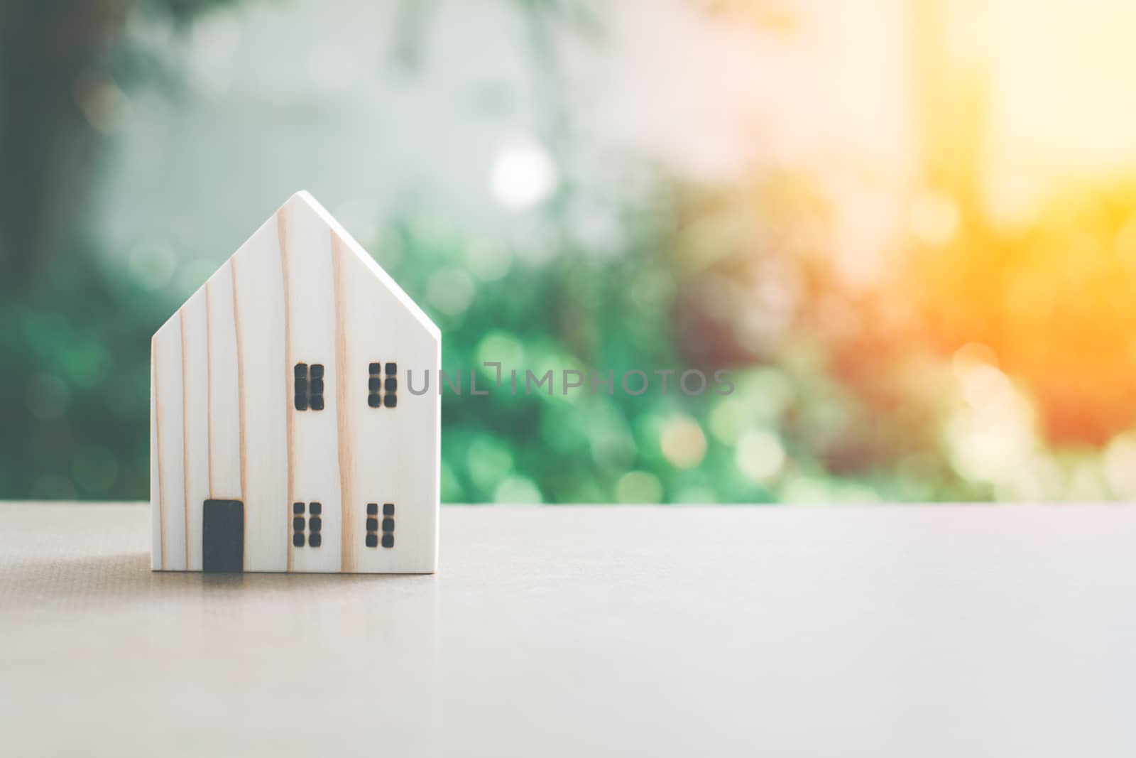 Eco home concept. Small wooden home model with green natural bokeh background with copy space.