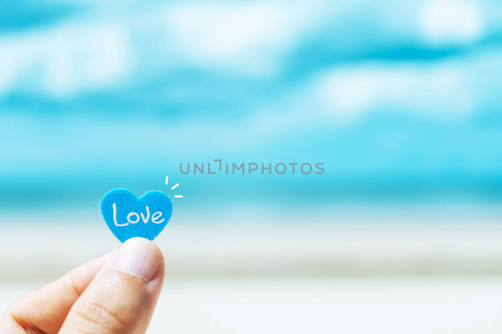 Hand hold little heart meaning feel love with summer beach with blue sky. by Suwant