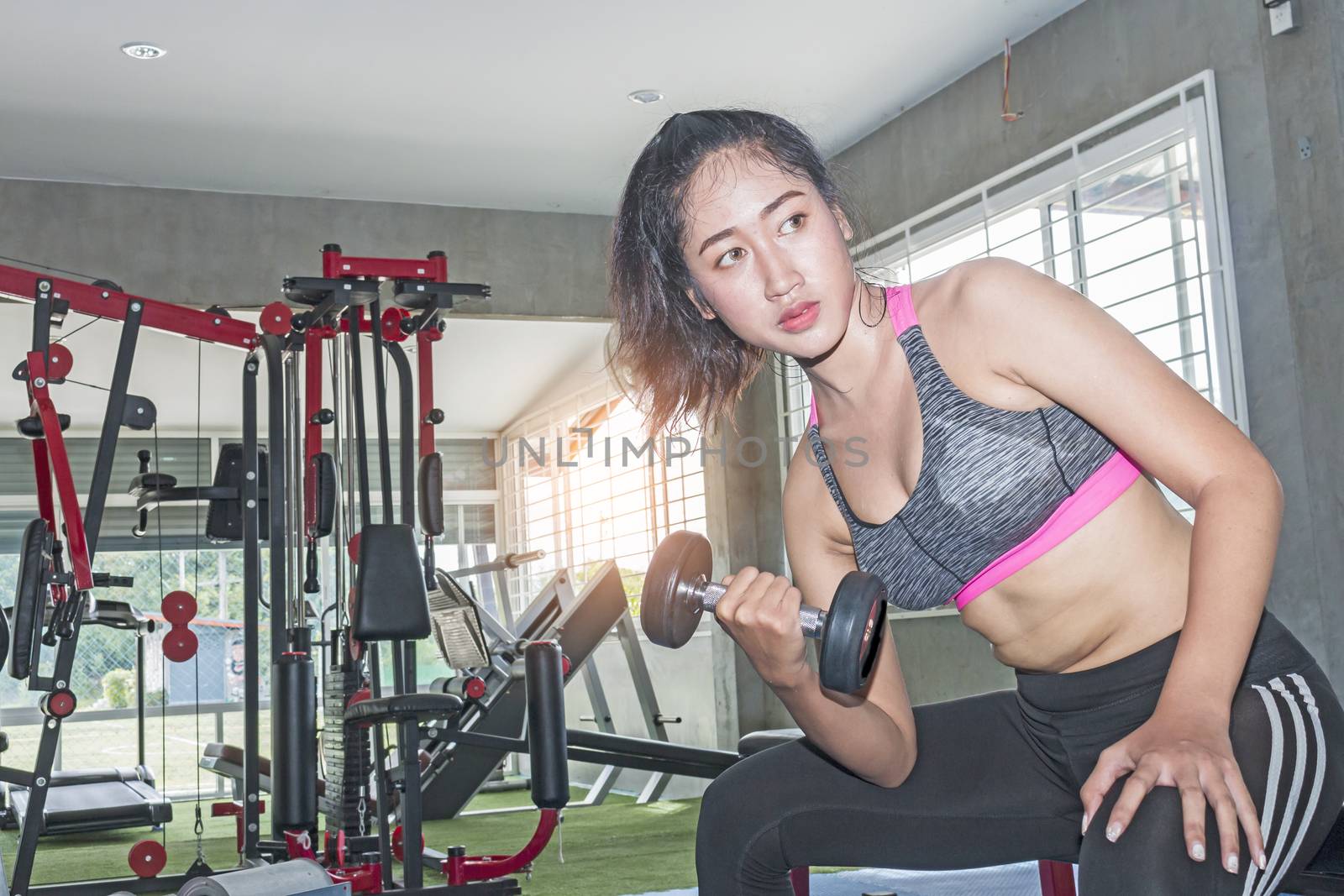 Asian  woman lifting weights in gym as part of her training