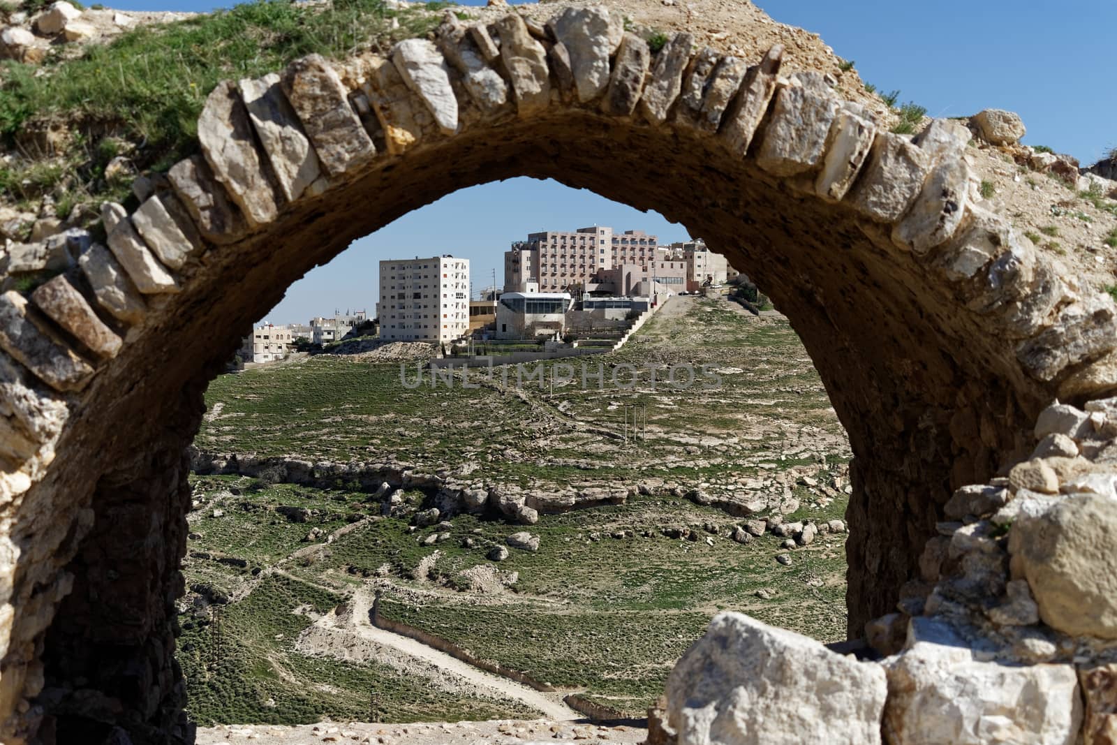 Skyscraper in the suburb of Karak in Jordan, photographed by a wall arch at the wall of the crusader castle by geogif