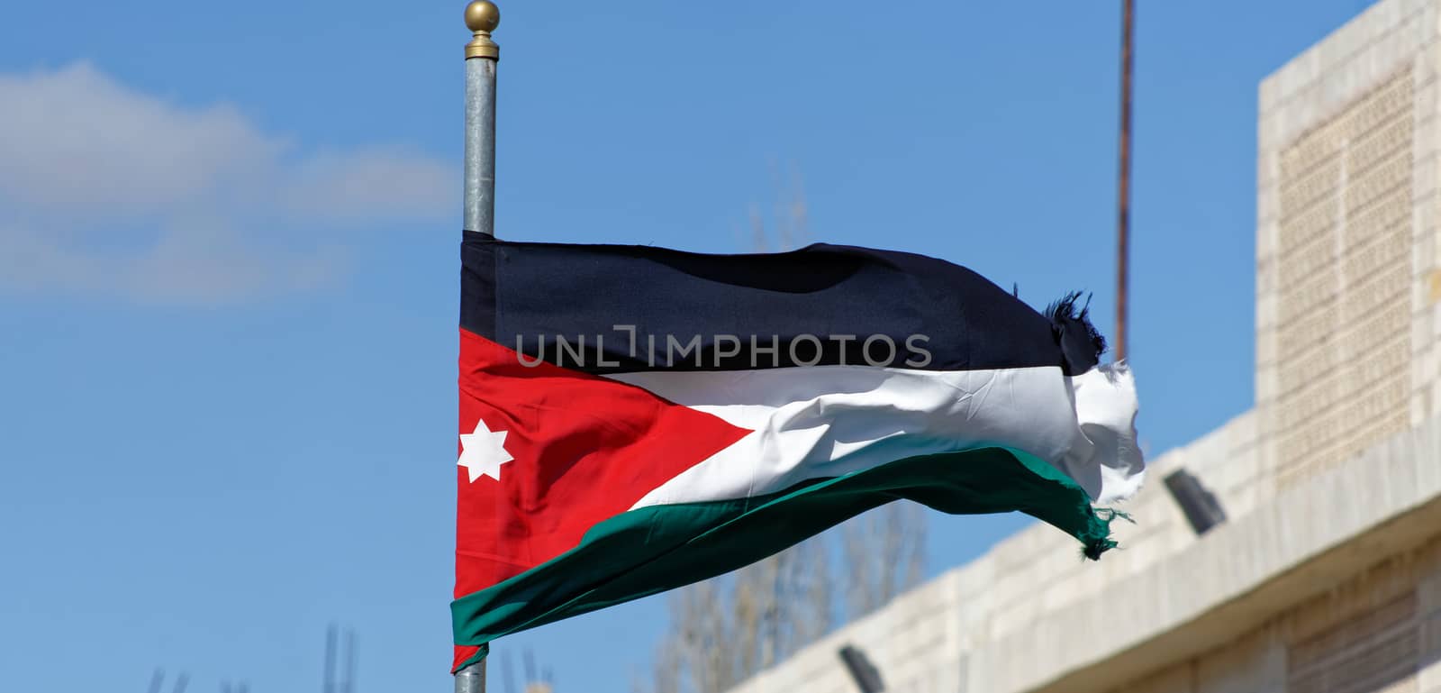 Jordanian flag waving in the wind in front of the tourist centre and visitor centre near the crusader castle in Karak, Jordan, middle east