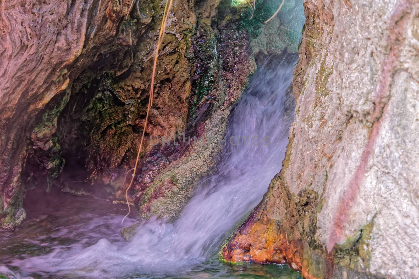 Small waterfall near a hot spring in Main, with colored precipitates of iron, copper, manganese and sulfur compounds, sinter