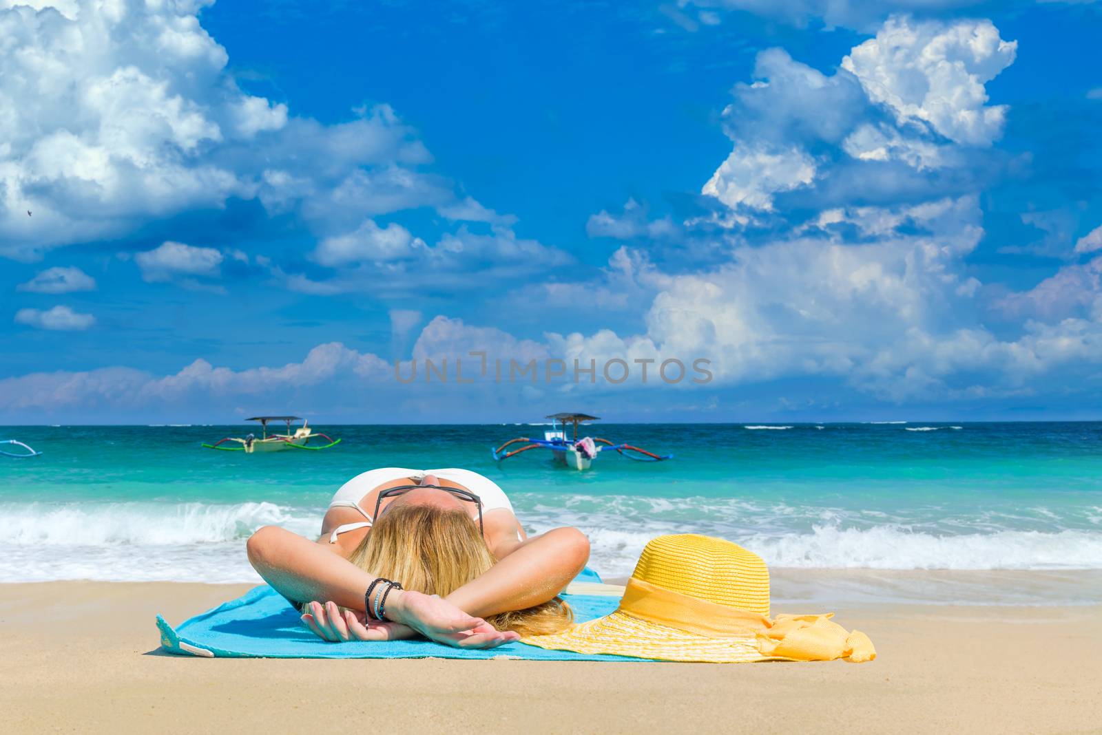 Woman in yellow bikini lying on tropical beach in Bali 