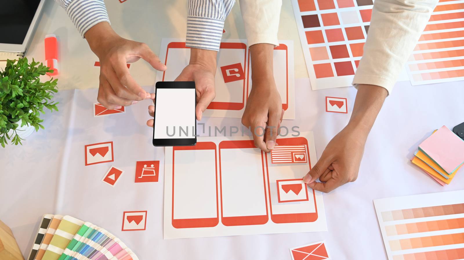 Cropped shot of UX UI Designer team are using the white blank screen mobile. UI UX Designer team are deciding about the icon.