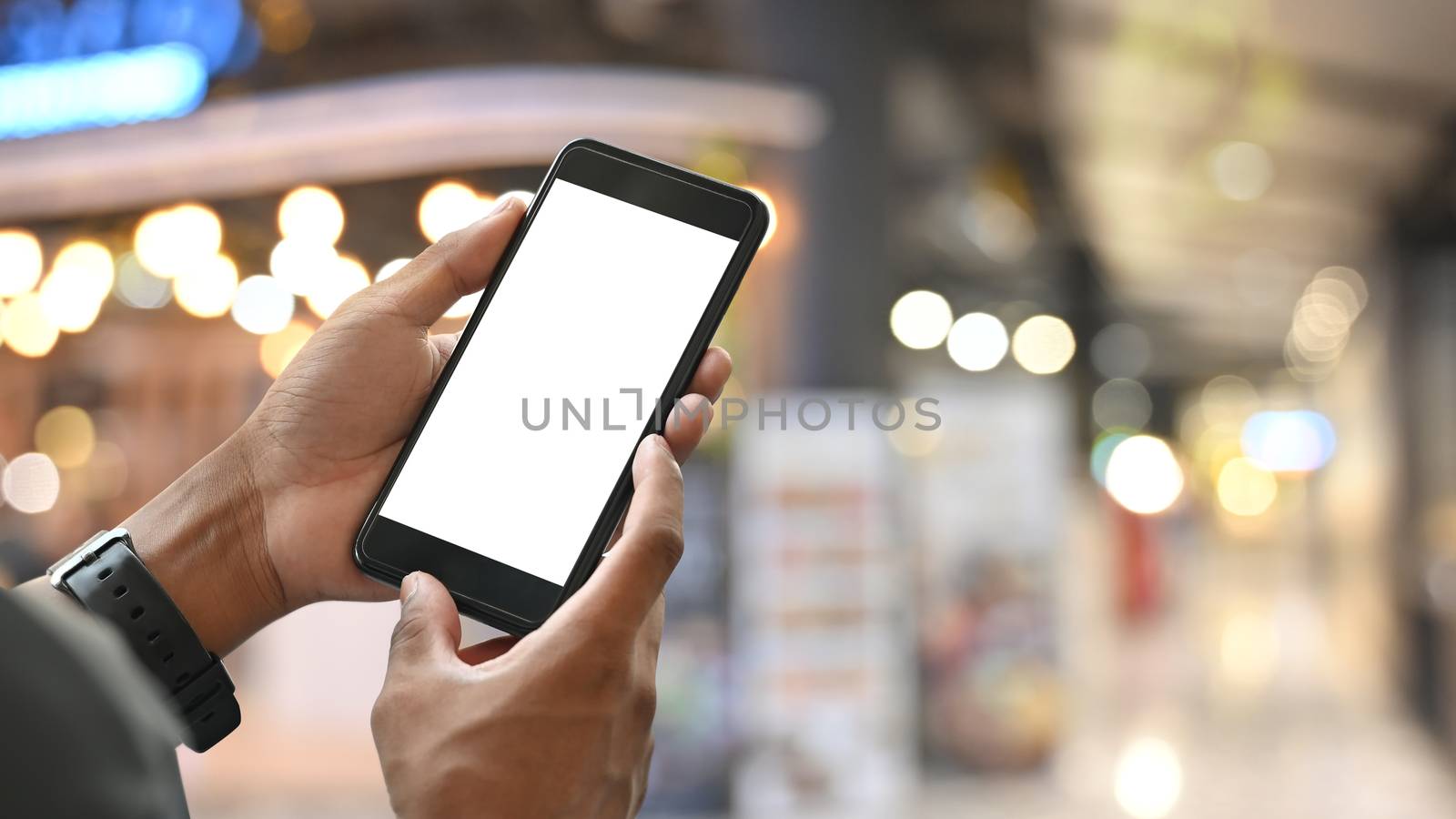 Cropped shot of hand while holding white blank screen smartphone by prathanchorruangsak