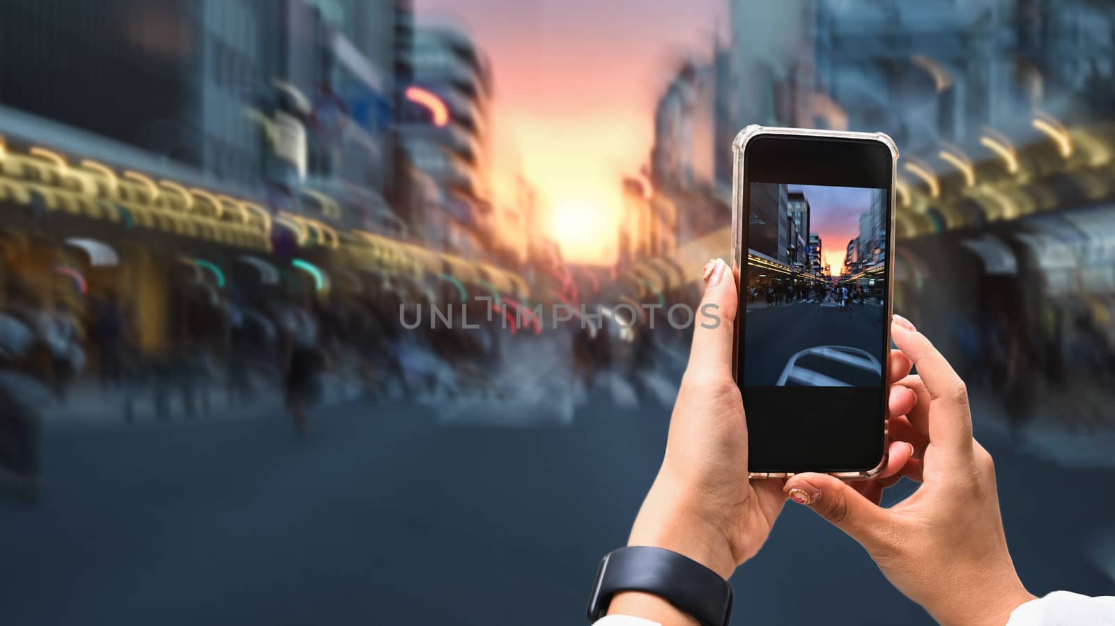 Close up image of woman hands taking a photo by use her smartphone  at dusk on pedestrian crossing.