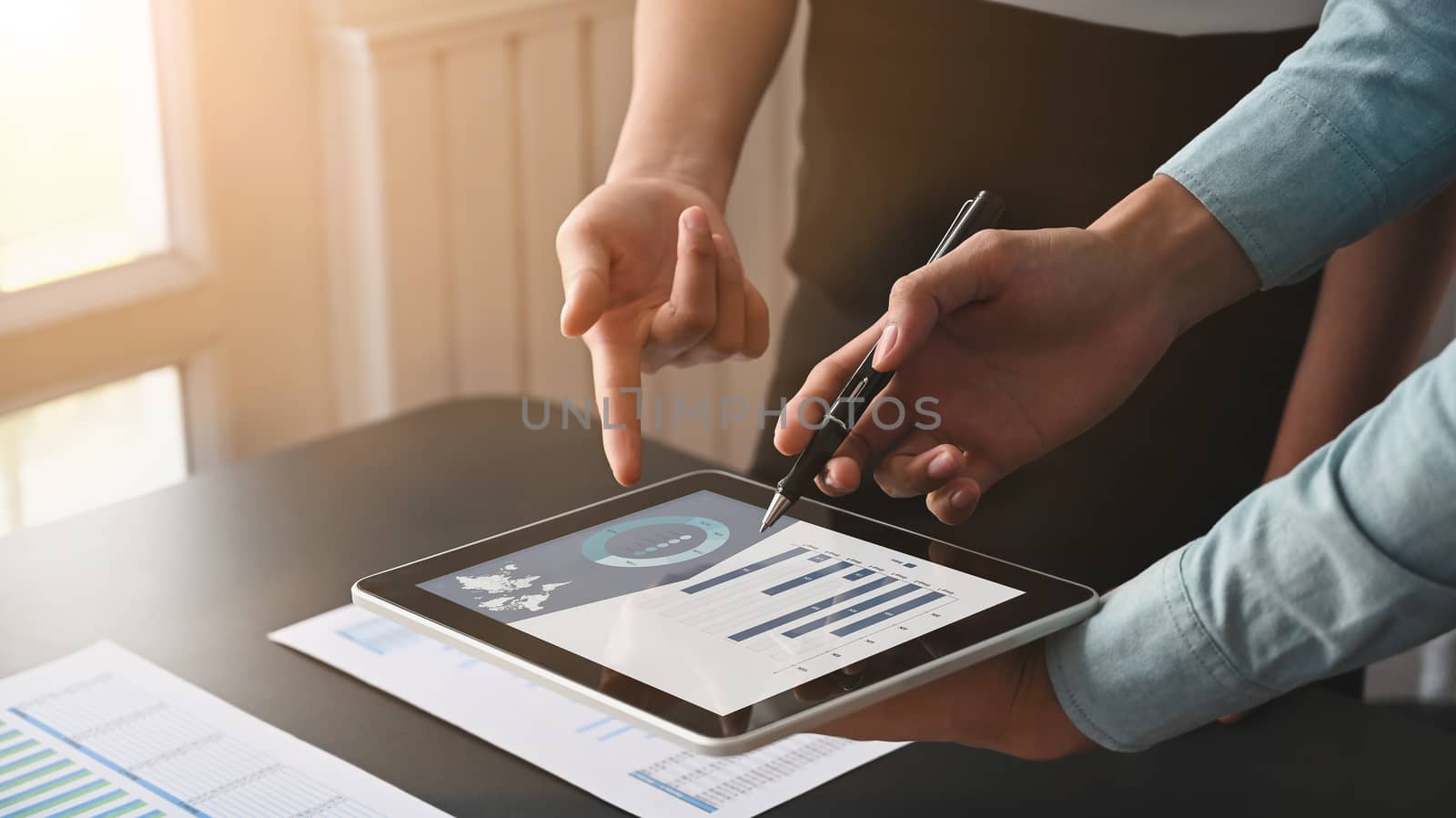 Close-up image of business team discussing financial analysis and development by using digital tablet with chart on screen.