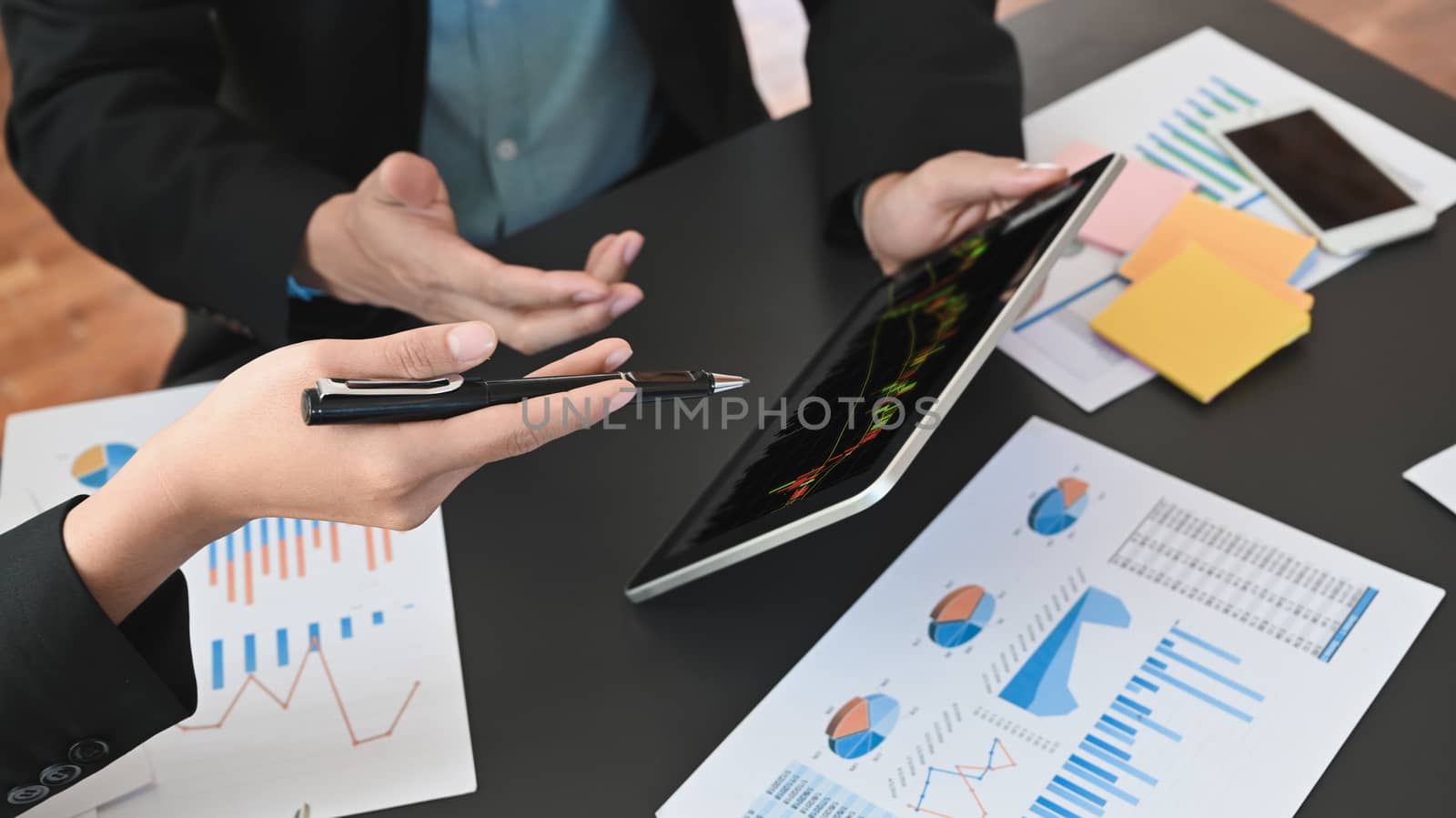 Cropped shot of businessmen discussing/analyzing about financial and business growing by using tablet with candle chart on screen.