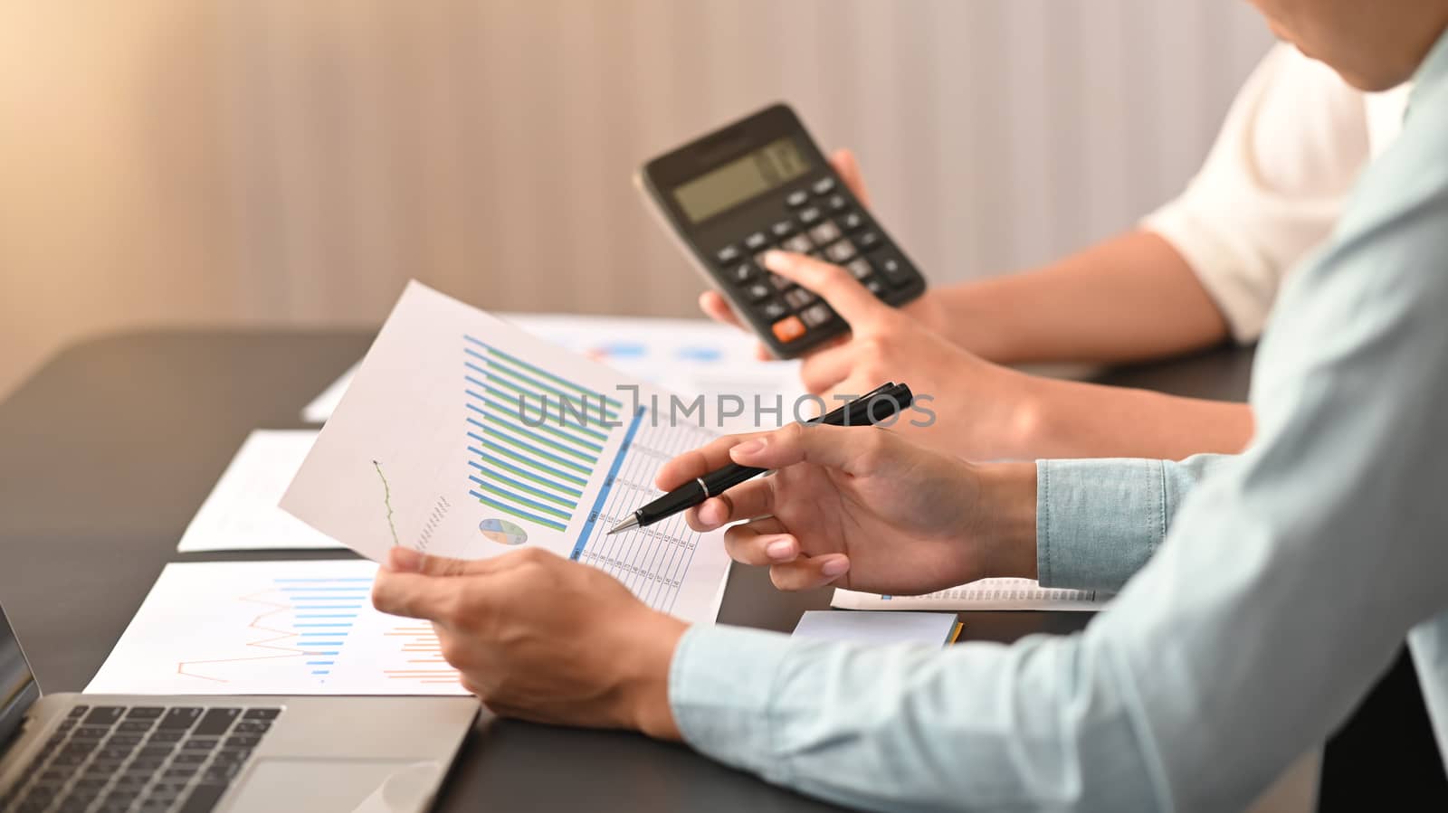 Side shot of young business development team are calculating /discussing/brainstorming at the modern meeting table. Chart analysis concept.