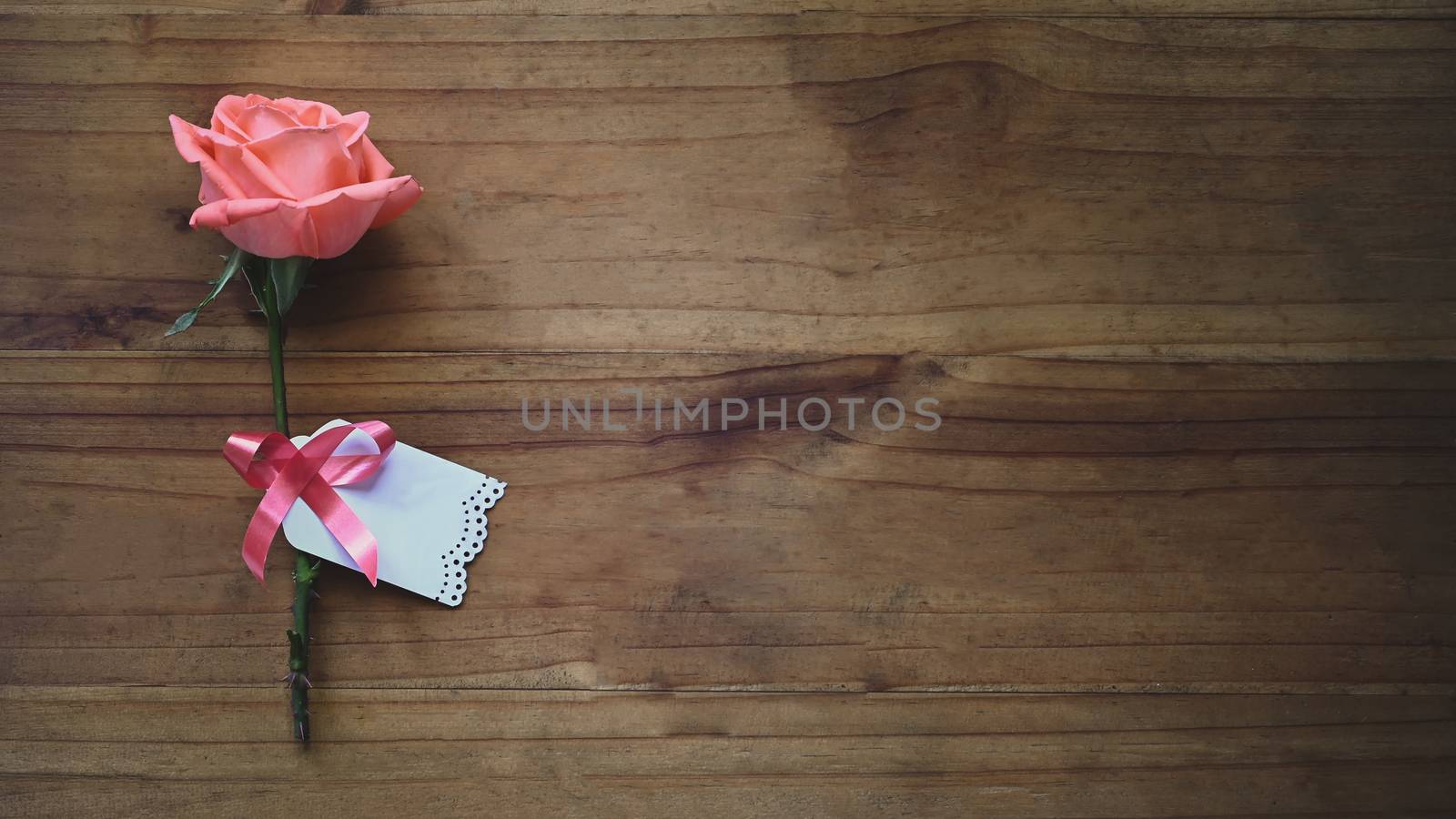 Top view image of pink rose and wishes card tied together with r by prathanchorruangsak