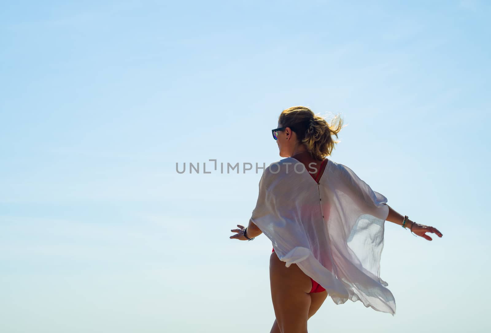 Woman enjoying her holidays at the tropical beach wearing a white summer top