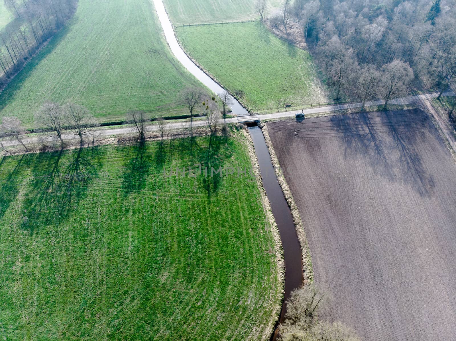 Aerial view of a stream flowing through meadows and fields under by geogif