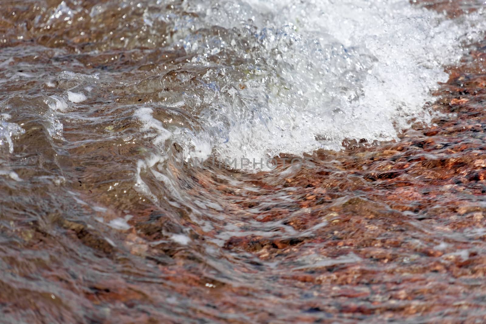 Detail of Small breaking wave at the beach of Aqaba in Jordan, covered with coarse gravel by geogif