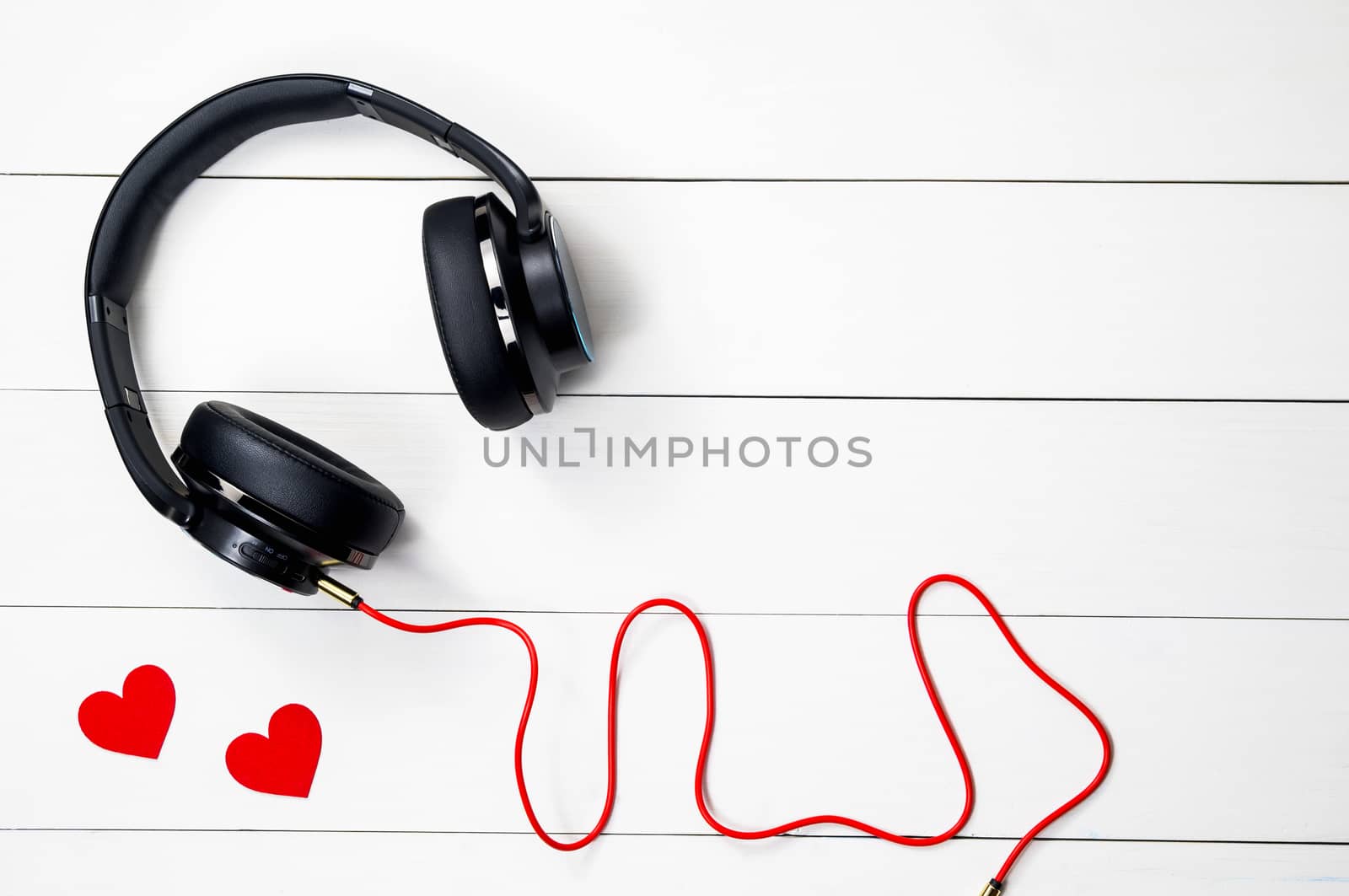 Black headphone and Red cable isolate on wood white table background,