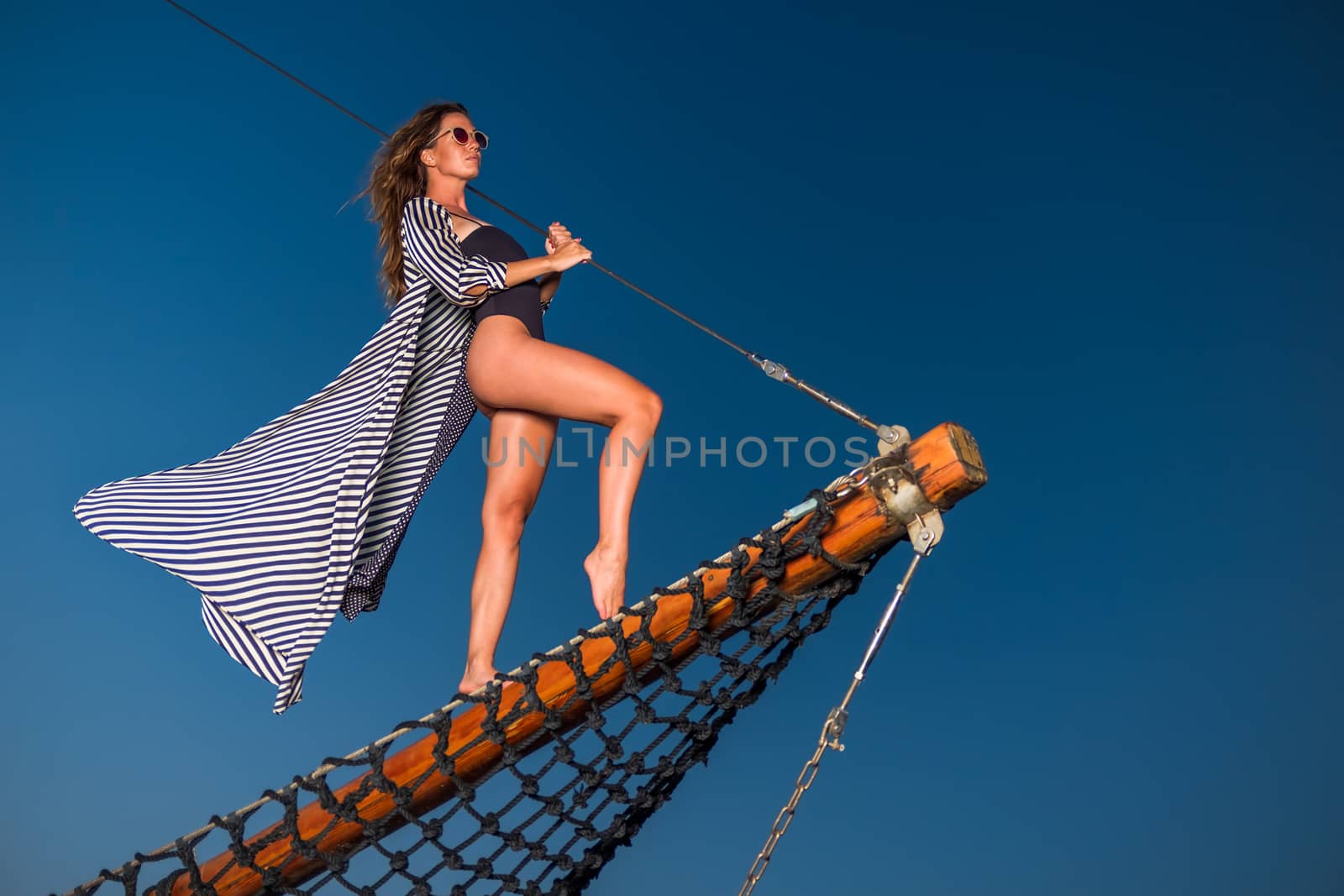 Beautiful young woman on a sailing boat  at sunset