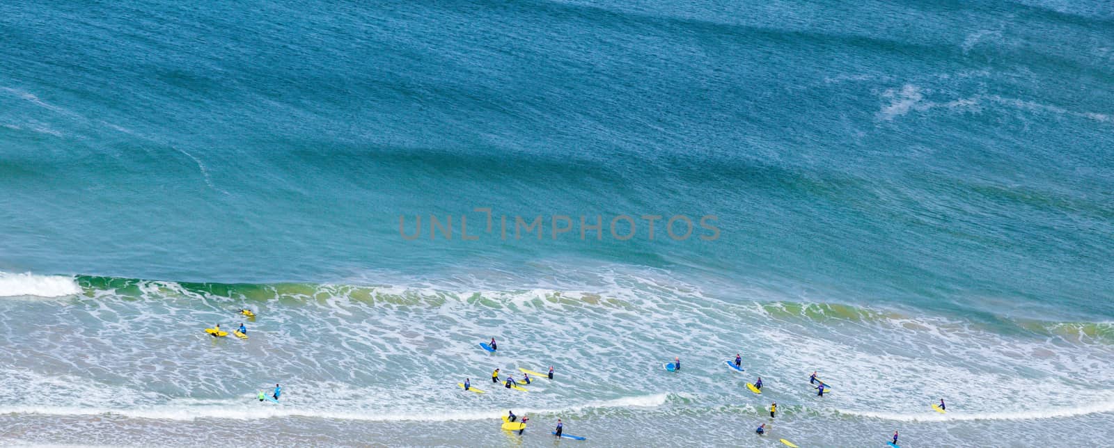 Surfers in the waves off Mawgan Porth Beach, Cornwall, UK