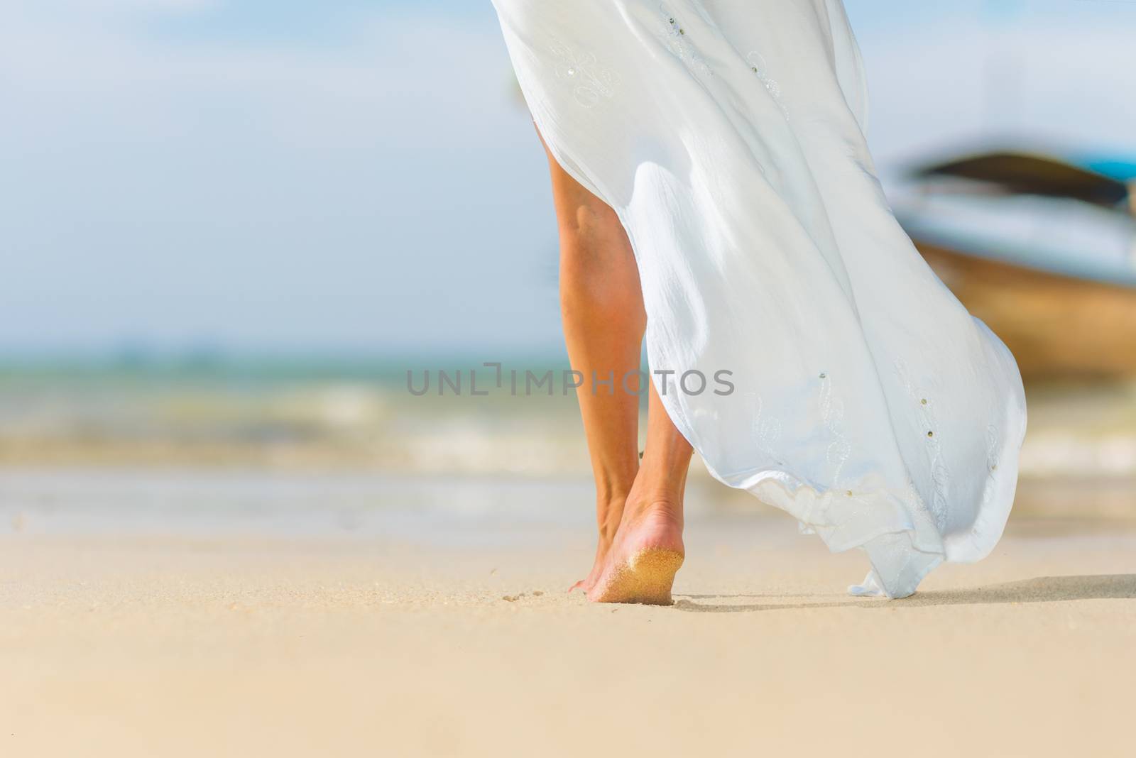 Closeup of barefoot female young adult lower body relaxing in ocean water on summer holiday