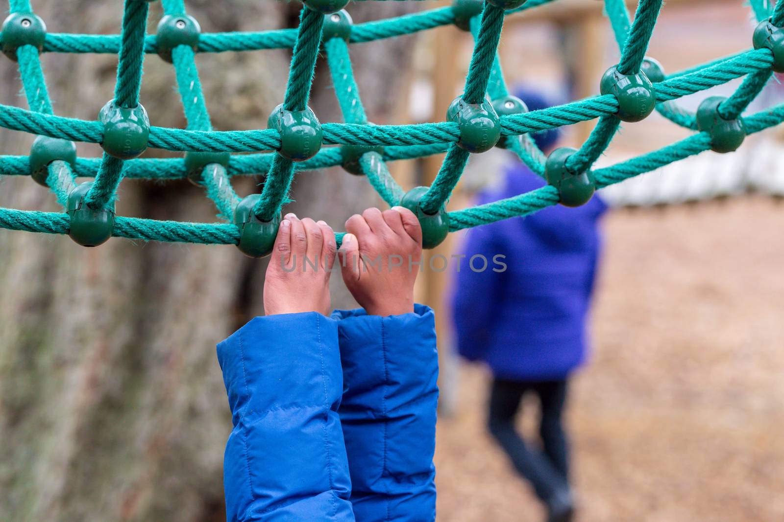 A young child hanging onto rope climbing equipment in Battersea Park, London