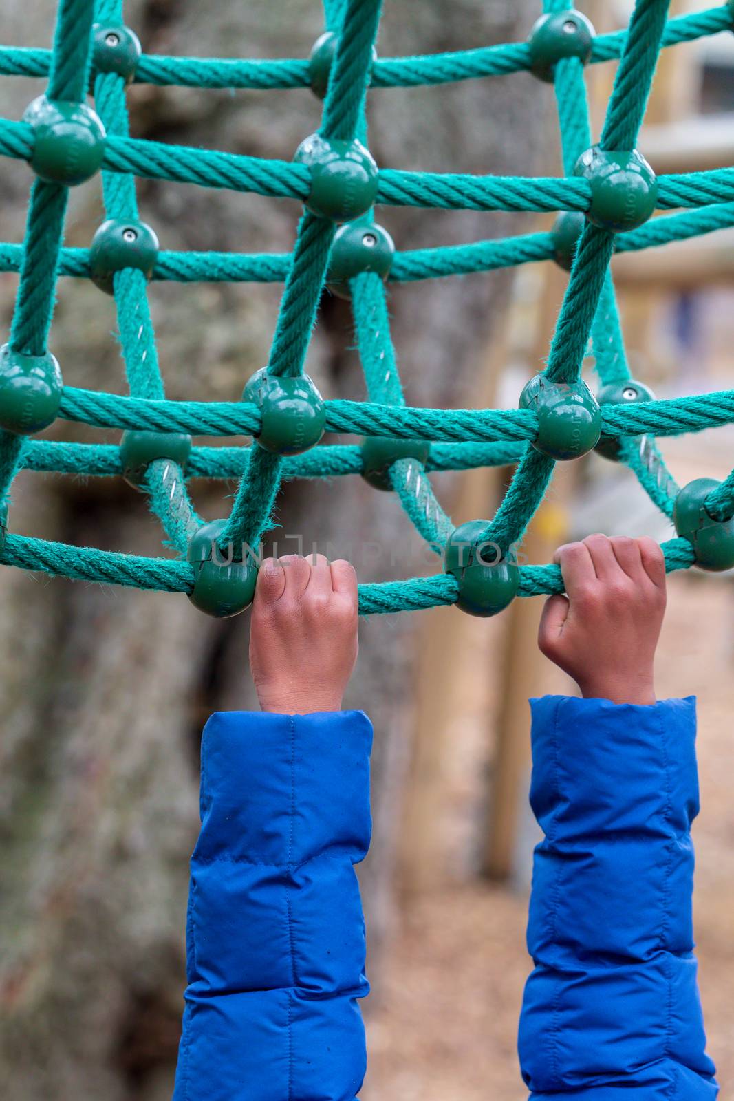 A young child hanging onto rope climbing equipment in Battersea Park, London