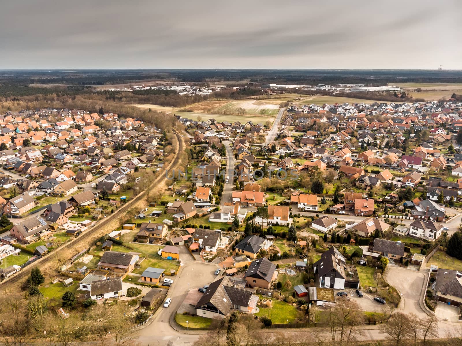 Aerial photos of a village in Germany crossed by a single-track railway line with grey sky in the background by geogif