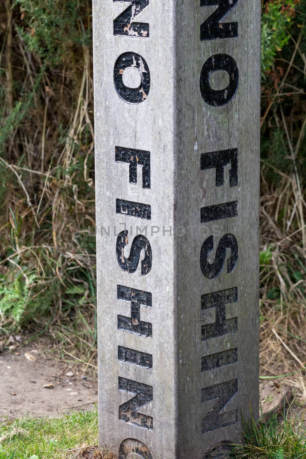 A vertical no fishing warning on a concrete post