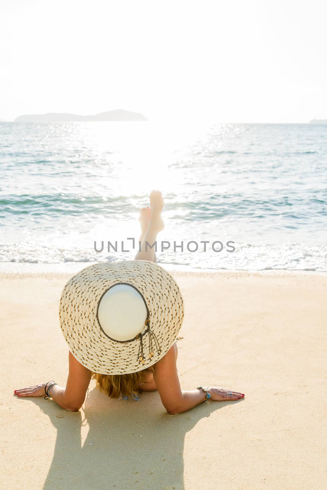 Young woman sitting on the beach.  by Netfalls