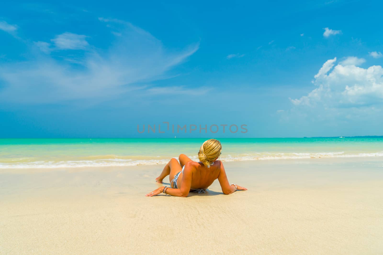 Woman laying on the sand on a beautiful tropical  beach 