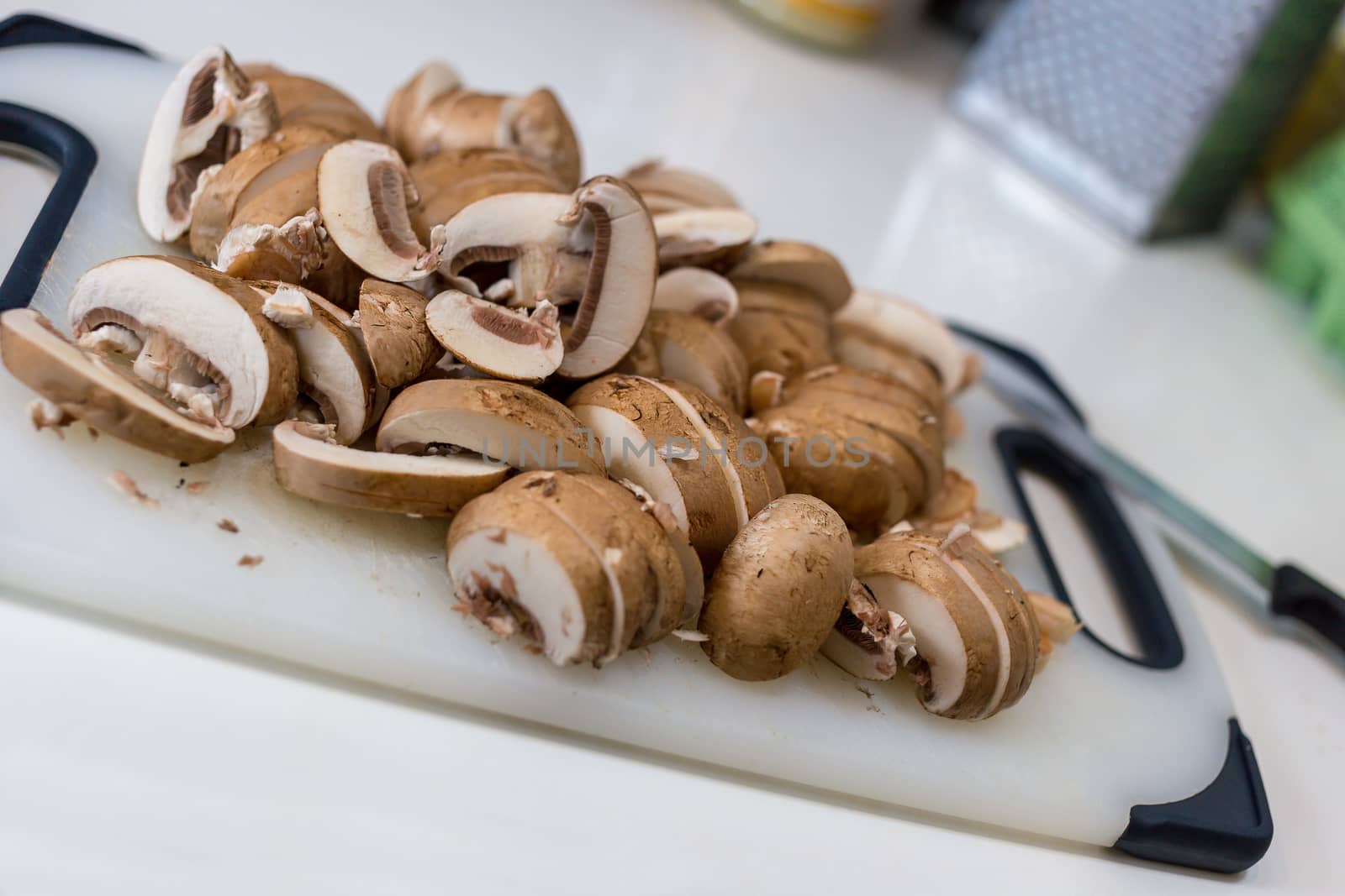 A pile of sliced chestnut mushrooms (Agaricus bisporus) on a white chopping board