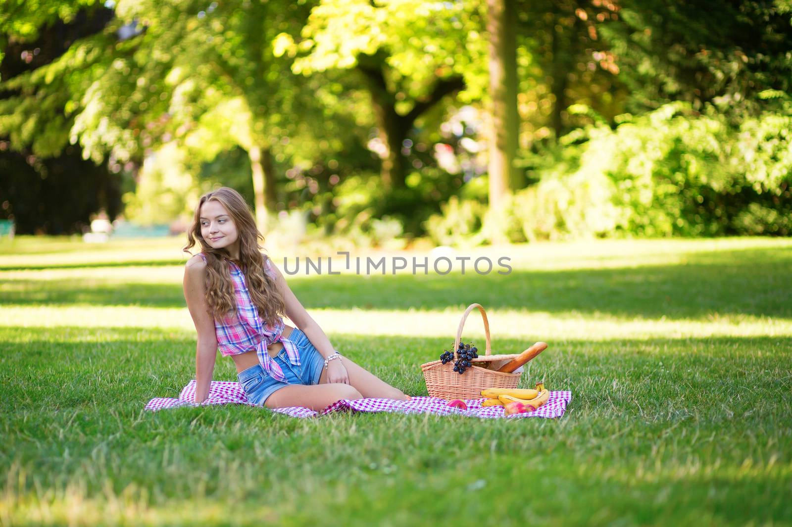 Pretty young girl having a picnic in park