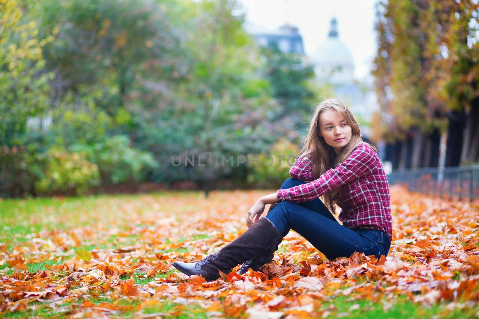 Thoughtful young girl sitting on the ground at fall
