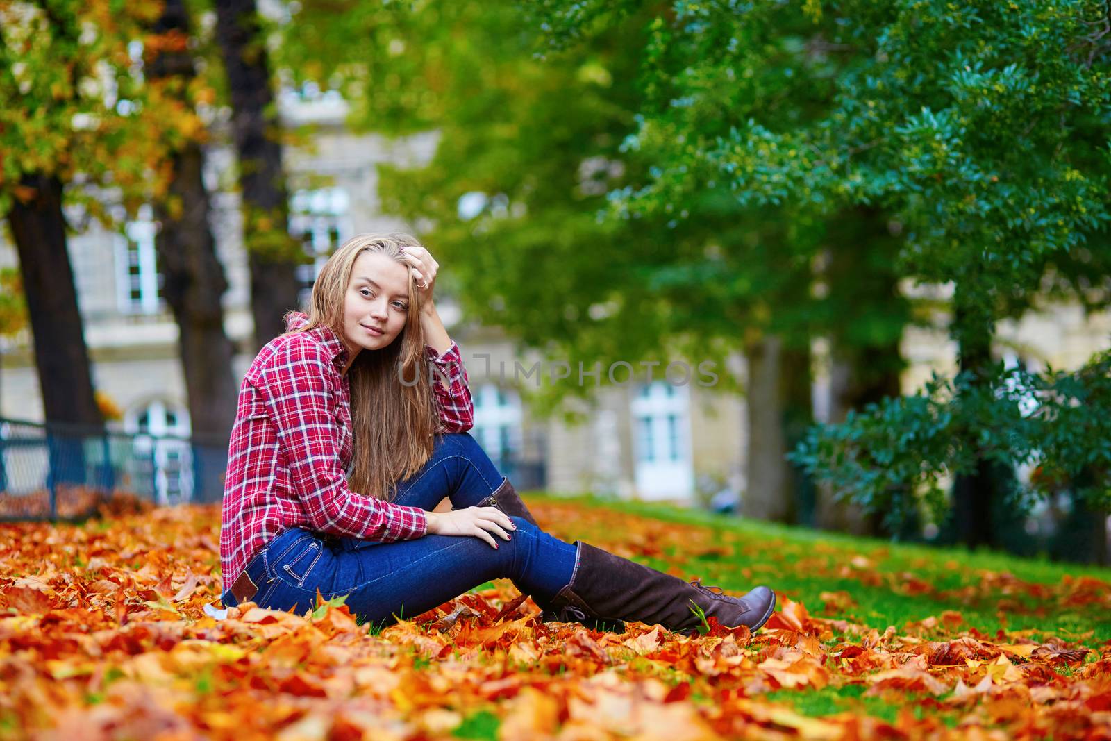 Thoughtful young girl sitting on the ground on a fall day