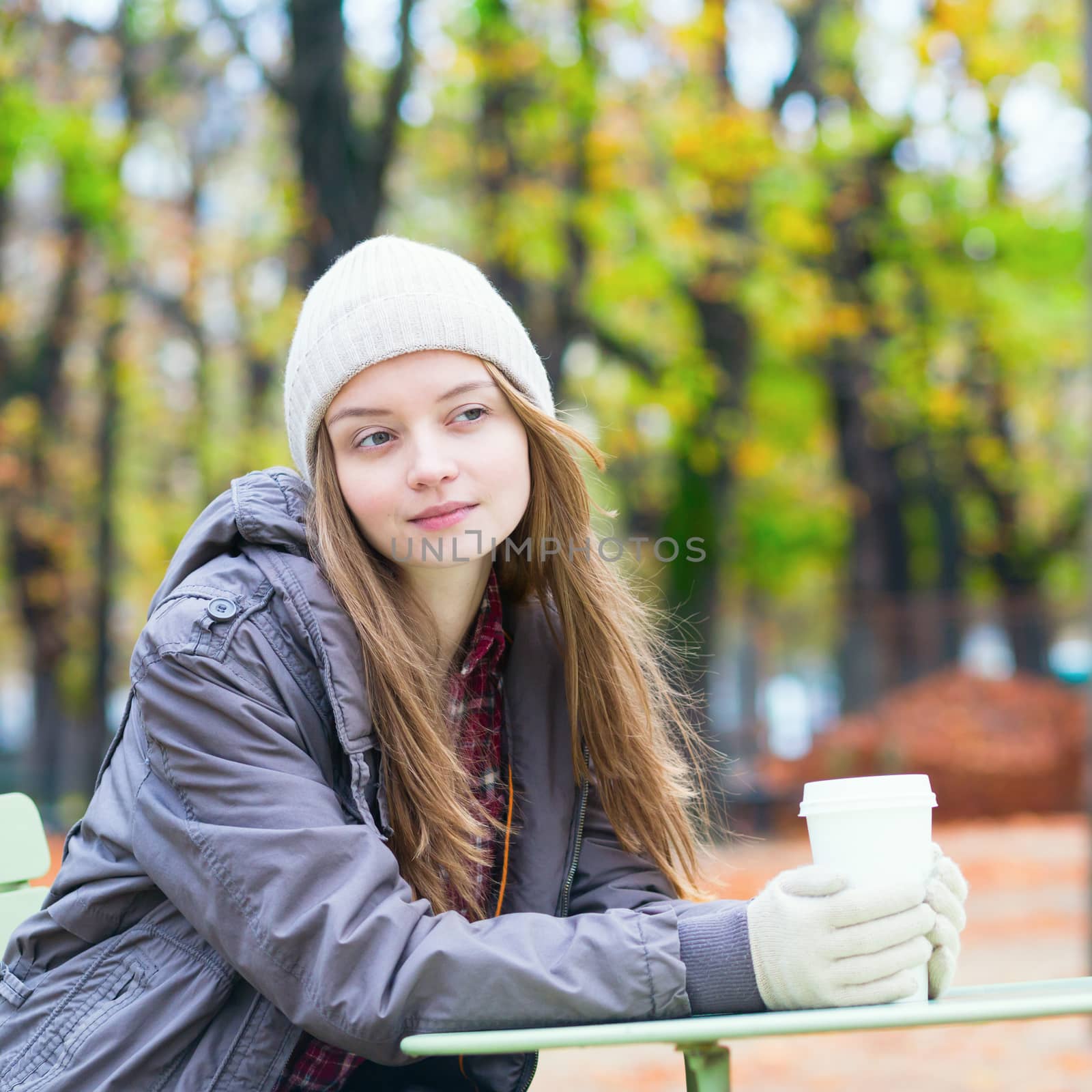 Young Parisian girl drinking coffee in the Luxembourg garden on a fall day