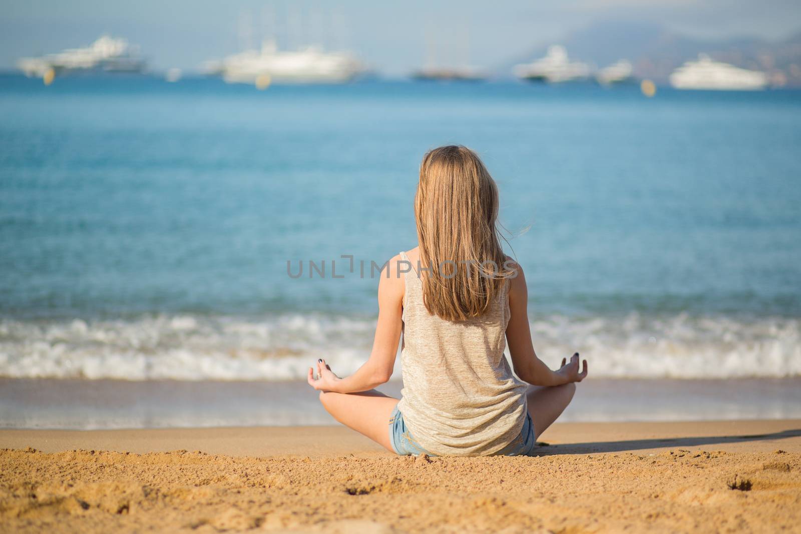 Young woman meditating on the beach by jaspe