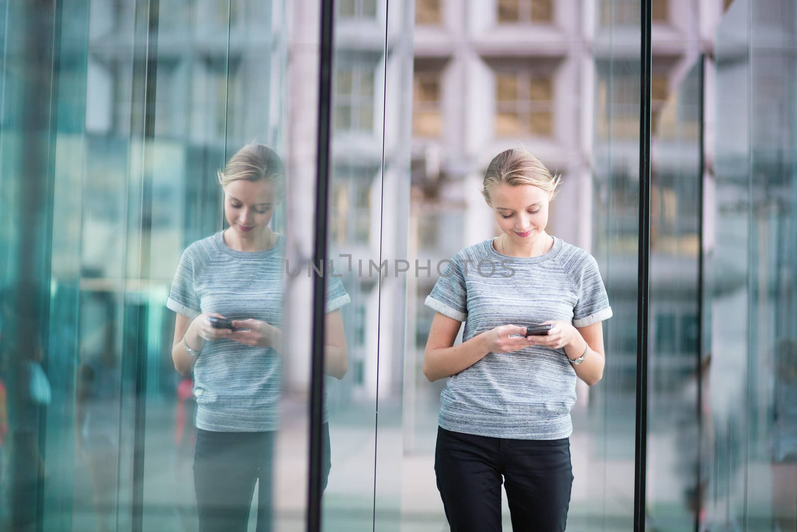 Young beautiful business woman in modern glass interior using the phone 