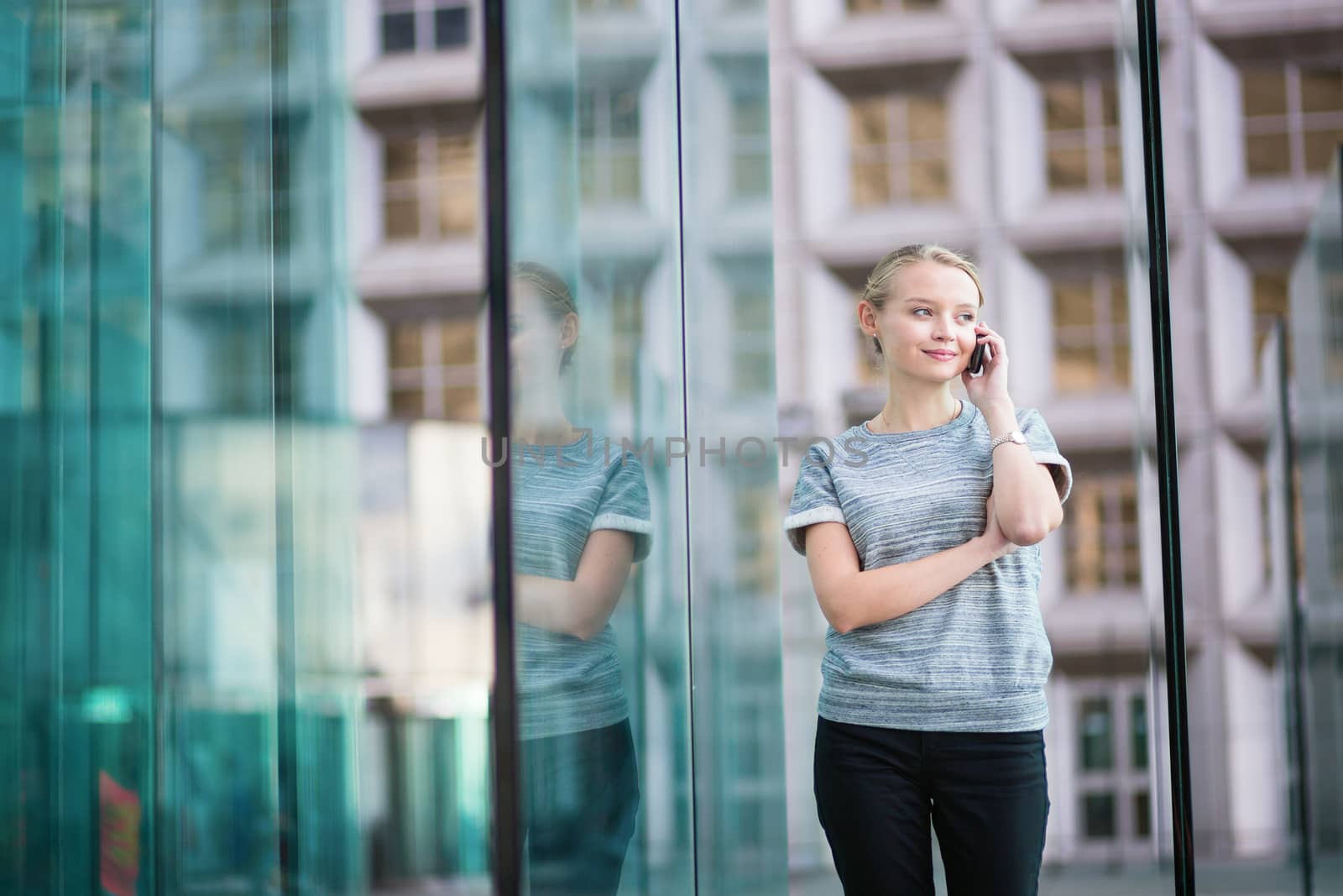 Young beautiful business woman in modern glass interior speaking on the phone