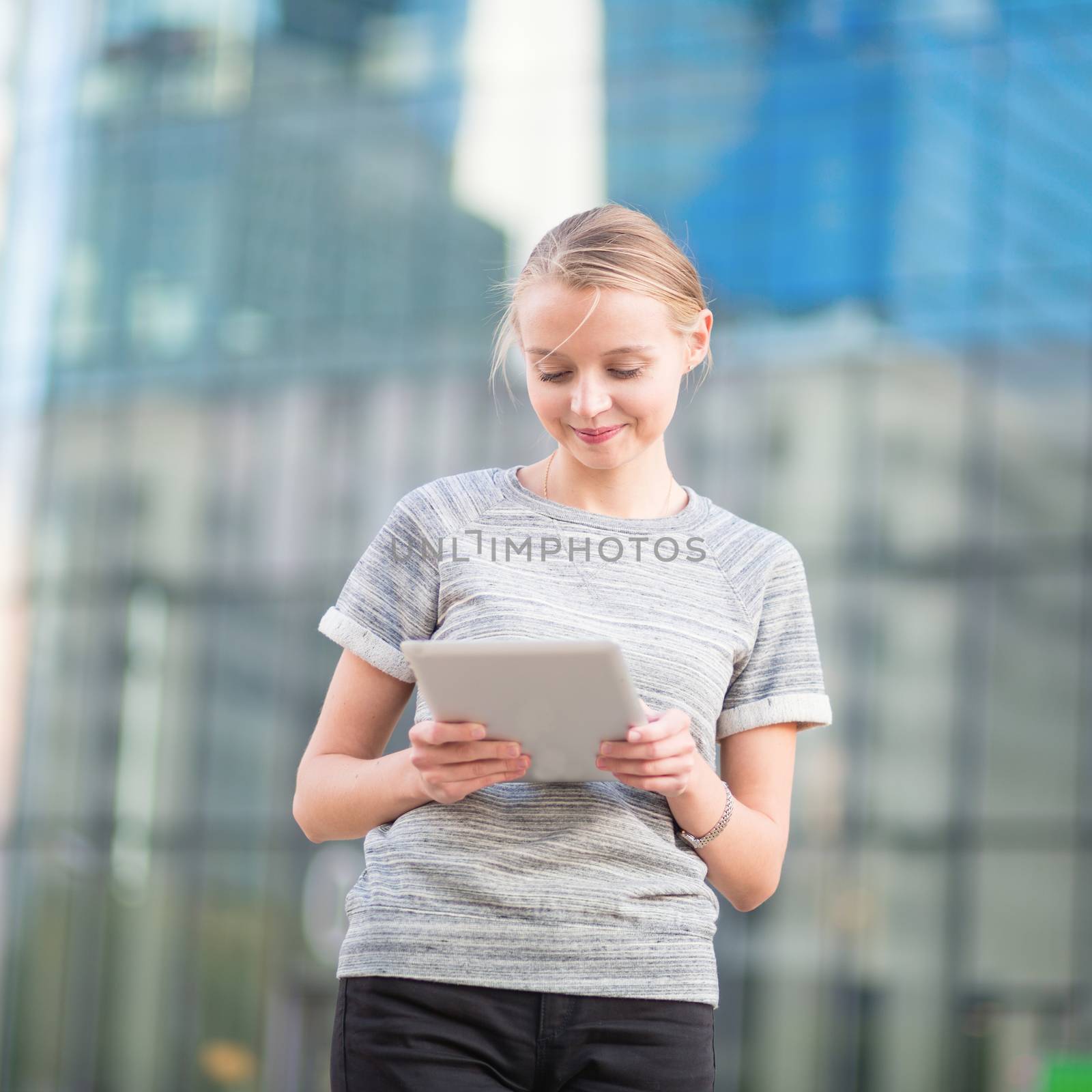 Young woman in office interior using tablet by jaspe