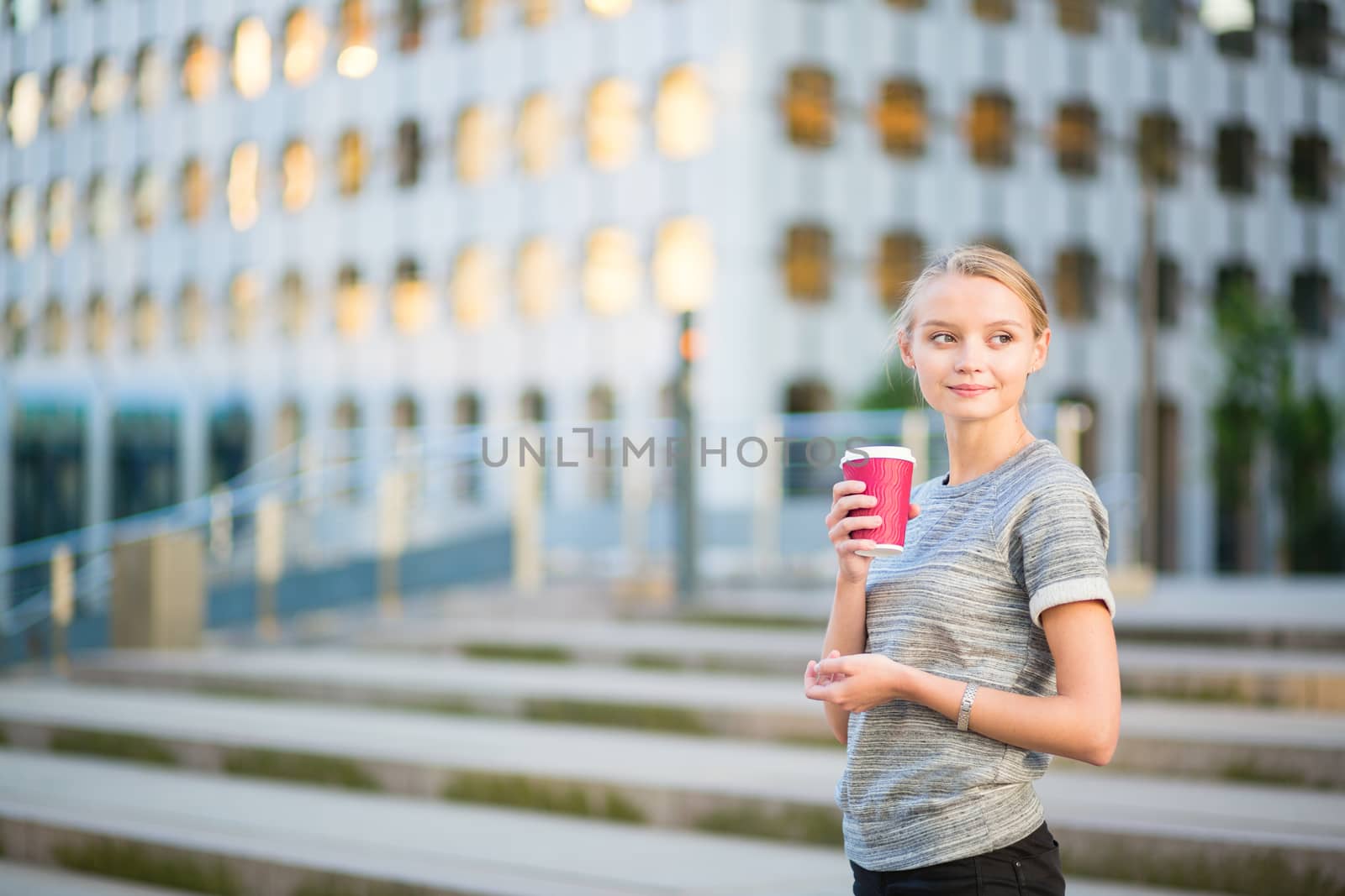 Young beautiful woman having her coffee break outside of the office or university