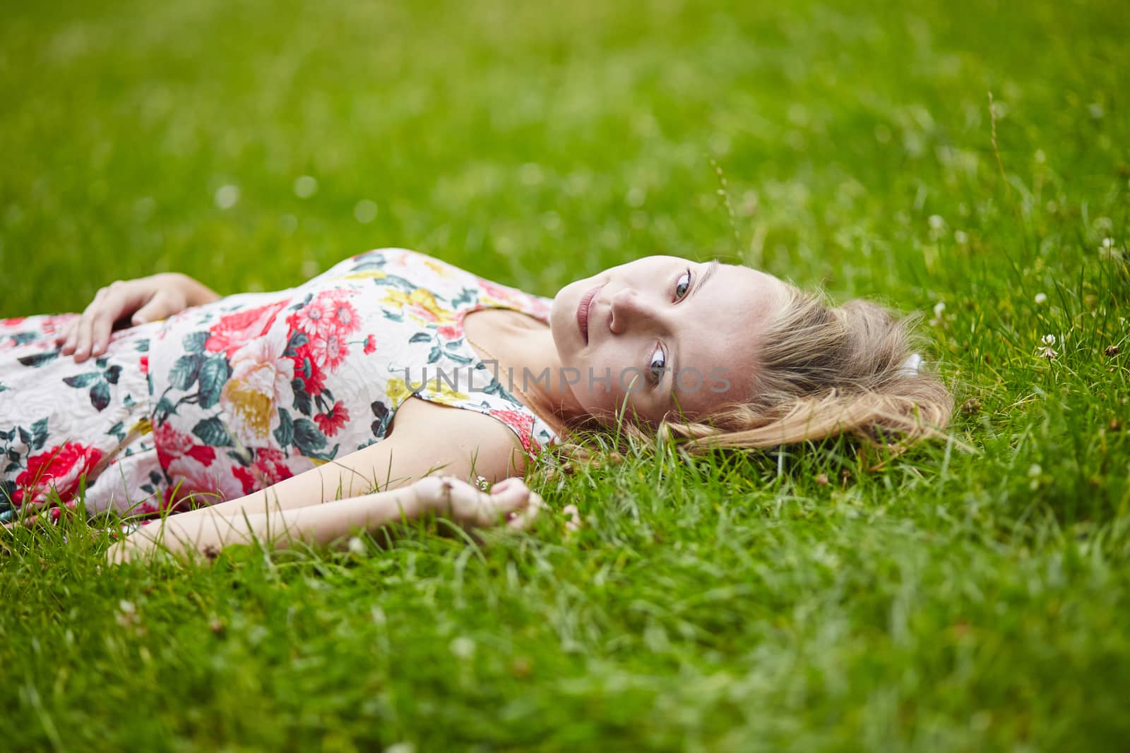 Beautiful young girl lying on the grass on a summer day 