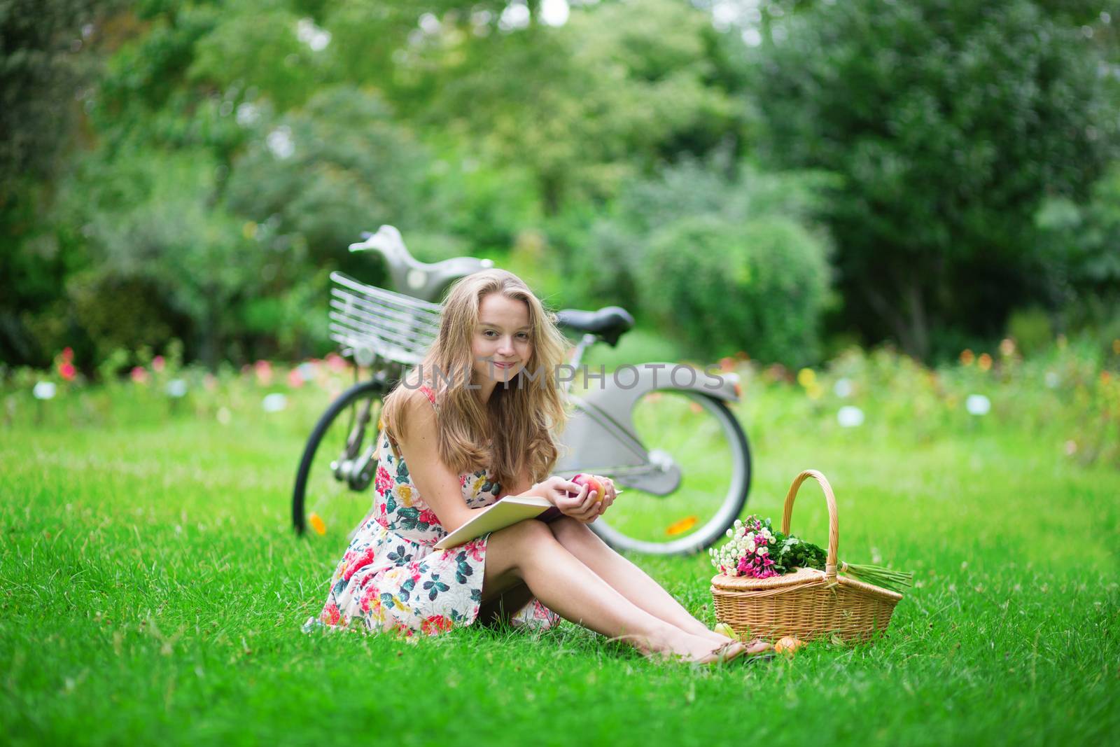 Beautiful young girl with bicycle in the countryside, reading a book