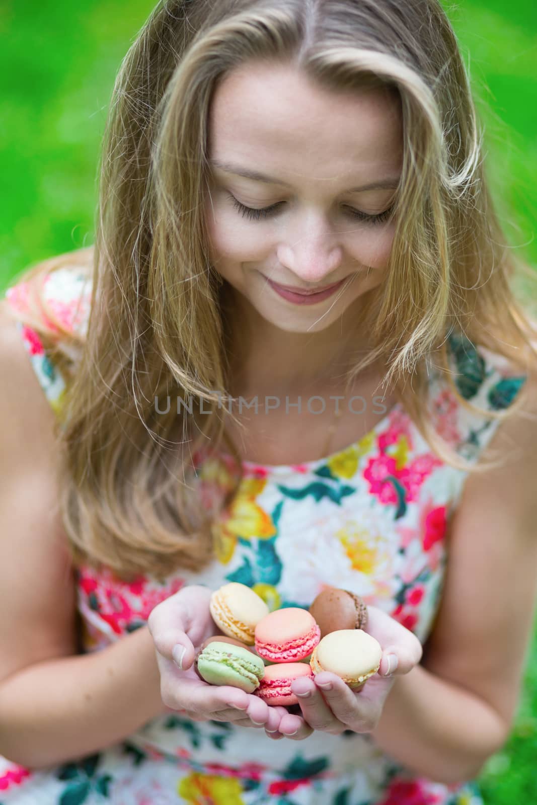 Beautiful young girl holding traditional French macaroons in hands