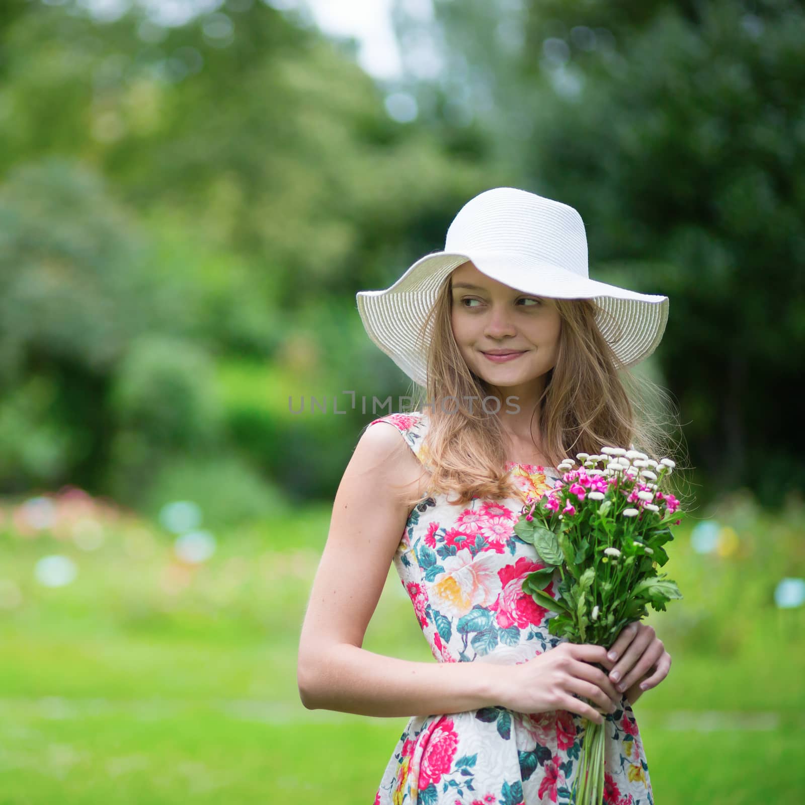 Young girl in white hat holding flowers by jaspe