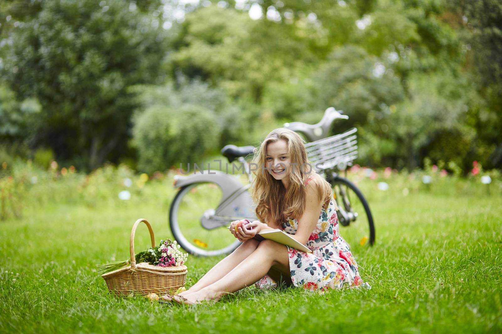 Beautiful young girl with bicycle in the countryside, reading a book