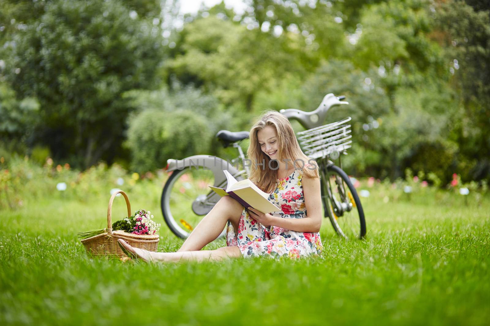 Beautiful young girl with bicycle in the countryside, reading a book
