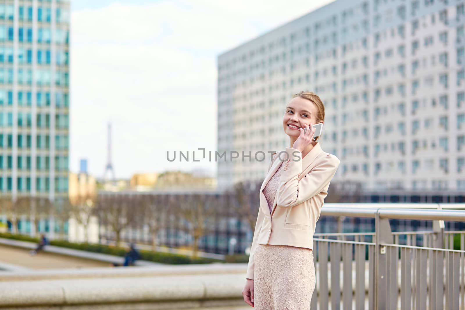 Young confident business woman in Paris using the mobile phone, Eiffel tower is in the background
