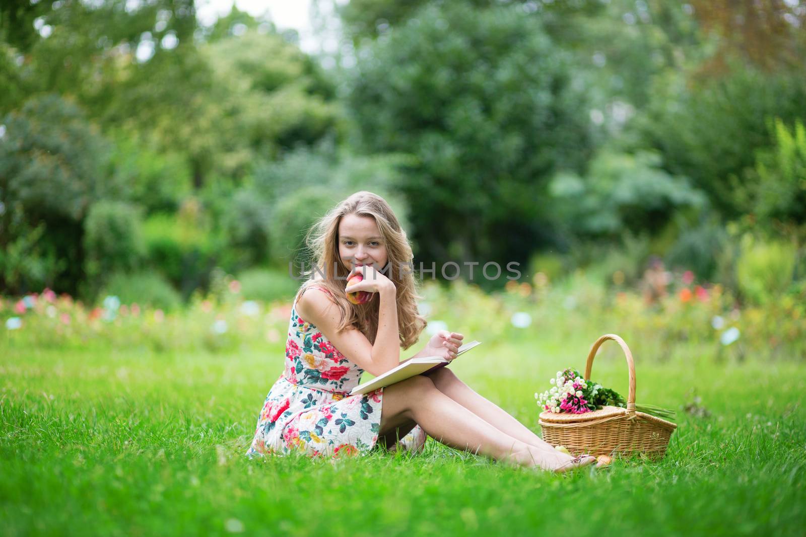 Beautiful young girl with bicycle in the countryside, reading a book